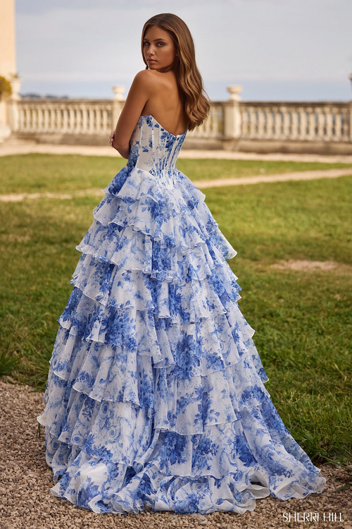 This dress features a floral blue print fabric with a strapless neckline and a satin corset bodice with a chiffon ruffle skirt and slit.

Sherri Hill 57250