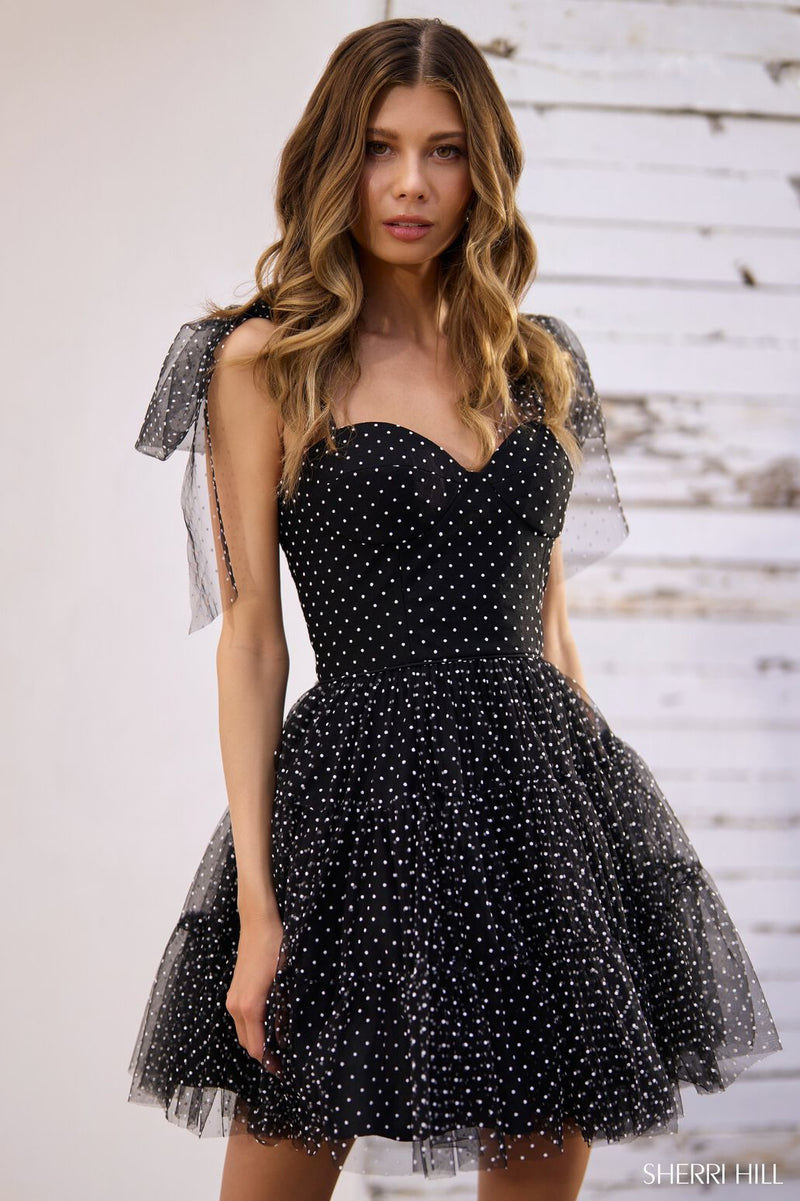 This cocktail dress features swiss dot tulle fabric with bow ties on the spaghetti straps. The A-line silhouette with the sweetheart neckline creates a feminine aesthetic that could be perfect for your next homecoming or formal event.  Sherri Hill 56506