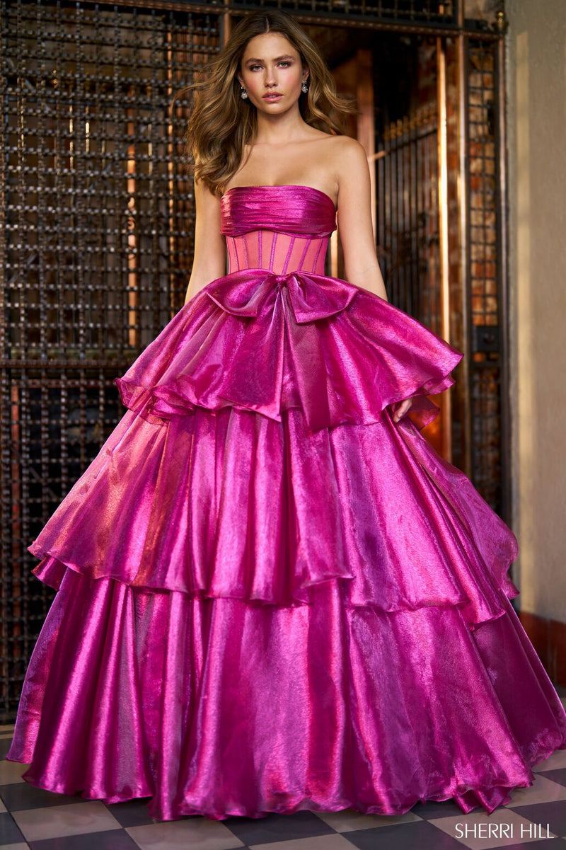 This strapless ballgown features a sheer corset bodice, a bow embellishment along the waistline, and ruffle tiered skirt with slit. This dress is dramatic and romantic and could be ideal for your next prom or formal event!  Sherri Hill 56767